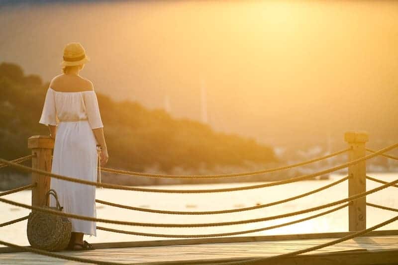 Foto di una donna in viaggio su un pontile che guarda il mare